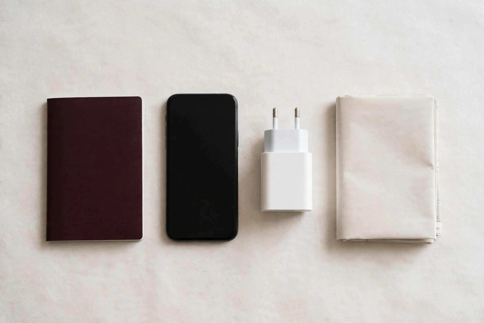 Travel essentials flat lay with passport, phone, adapter and map